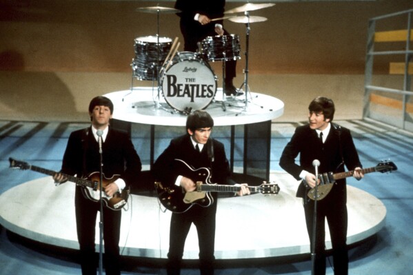 FILE -The Beatles, foreground from left, Paul McCartney, George Harrison, John Lennon and Ringo Starr on drums perform on the CBS "Ed Sullivan Show" in New York on Feb. 9, 1964. Sixty years after the onset of Beatlemania and with two of the quartet now dead, artificial intelligence has enabled the release of a “new” Beatles song.“Now And Then,” will be available Thursday, Nov. 2. (AP Photo/File)