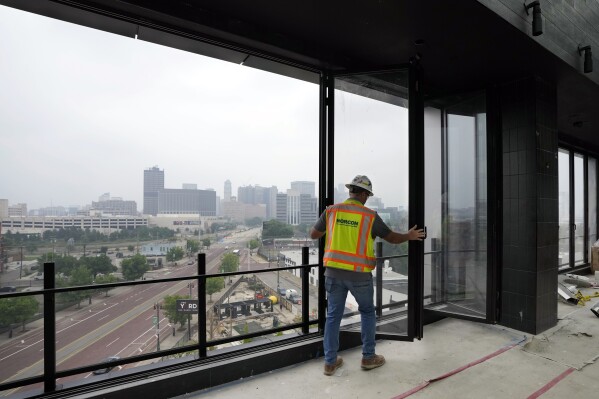 A worker opens the windows on the top floor of the new Godfrey Hotel, June 27, 2023, in Detroit. On July 18, 2013, a state-appointed manager made Detroit the largest U.S. city to file for bankruptcy. A decade later, the Motor City has risen from the ashes of insolvency. Corktown, a neighborhood just east of downtown, got a boost in 2018 when Ford Motor Co. bought and began renovating the train station. Ford's move has attracted other investment, according to Aaron Black, the general manager of the nearby $75 million Godfrey Hotel, which is scheduled to open later in 2023. (AP Photo/Carlos Osorio)