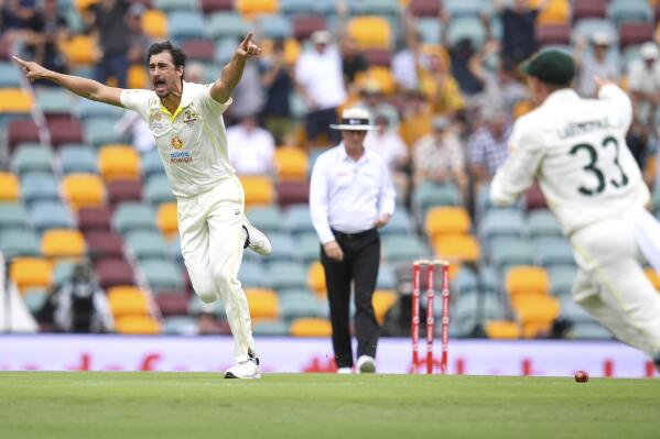 Australia's Mitchell Starc, left, celebrates after taking the wicket of England's Rory Burns during day one of the first Ashes cricket test between Australia and England at The Gabba in Brisbane, Australia, Wednesday, Dec. 8, 2021. (Darren England/AAP Image via AP)