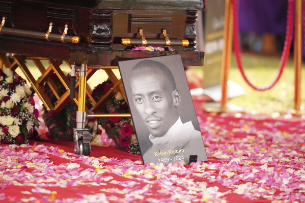 A portrait of Kelvin Kiptum next to his casket is seen ahead of his burial, in Elgeyo Marakwet, Kenya, Friday Feb. 23, 2024. World marathon record holder Kelvin Kiptum was buried Friday following his death in a road accident, as Kenyans castigated the government for not doing enough to protect and support country's famed athletes. (AP Photo/Brian Inganga)