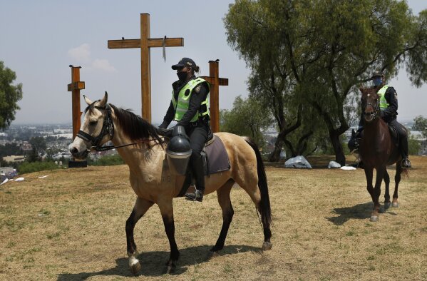 Mounted police guard the La Estrella hill where crosses are located for an annual Holy Week Via Crucis in Iztapalapa, Mexico City, Thursday, April 9, 2020. The area is closed and the police are preventing people from making to the area as a way to help slow down the spread of the new coronavirus. (AP Photo/Marco Ugarte)