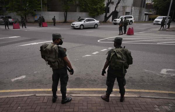 Security officers stand guard a day after clashes between government supporters and anti government protesters in Colombo, Sri Lanka, Tuesday, May 10, 2022. Defying a nationwide curfew in Sri Lanka, several hundred protesters continued to chant slogans against the government Tuesday, a day after violent clashes saw the resignation of the prime minister who is blamed, along with his brother, the president, for leading the country into its worst economic crisis in decades. (AP Photo/Eranga Jayawardena)