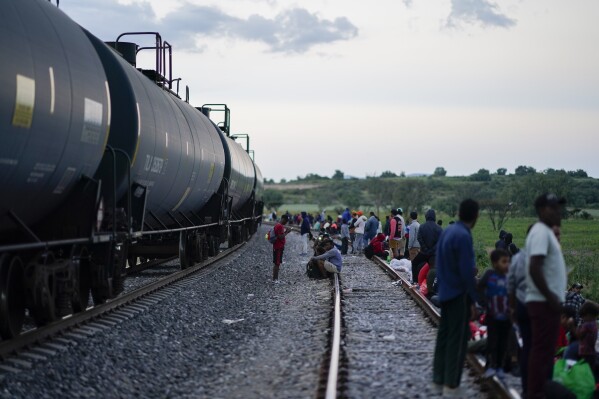 Migrants watch a train go past as they wait along the train tracks hoping to board a freight train heading north, in Huehuetoca, Mexico, Sept. 19, 2023. Ferromex, Mexico's largest railroad company announced that it was suspending operations of its cargo trains due to the massive number of migrants that are illegally hitching a ride on its trains moving north towards the U.S. border. (AP Photo/Eduardo Verdugo)