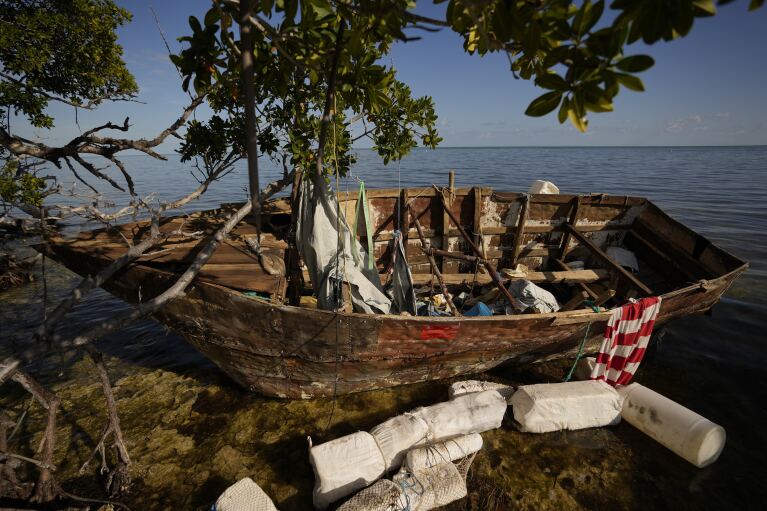 FILE - A wooden migrant boat lies grounded on a reef alongside mangroves, at Harry Harris Park in Tavernier, Fla., Jan. 19, 2023. Increasing numbers of Cuban and Haitian migrants have attempted the risky Florida Straits crossing in recent months to illegally enter the Keys Island chain and other parts of the state as inflation soars and economic conditions deteriorate in their home countries. (AP Photo/Rebecca Blackwell, File)