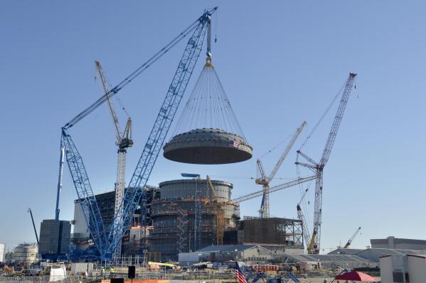 A large dome is lowered onto a nuclear containment building at the Plant Vogtle nuclear energy facility in Waynesboro, Ga., Friday, March 22, 2019. The cost of two new reactors being built there is now at least $28.5 billion, more than twice the original price tag, with the other owners saying Georgia Power Co. has triggered an agreement requiring Georgia Power to pay more of the costs. (Michael Holahan/The Augusta Chronicle via AP)
