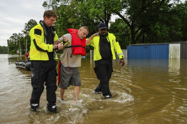 FILE - Tim McCanon, center, is rescued by the Community Fire Department during severe flooding on Friday, May 3, 2024, in New Caney, Texas. In a world growing increasingly accustomed to wild weather swings, the last few days and weeks have seemingly taken those environmental extremes to a new level. (Raquel Natalicchio/Houston Chronicle via AP, File)
