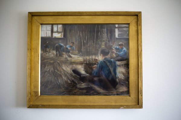FILE - In this file photo taken on April 5, 2017, Max Liebermann's "Basket Weavers" painting hangs in a law office in Jerusalem. The painting was returned to David Toren, an American heir of its original Jewish owner, after he sued the government of Germany for his great-uncle’s collection and after a lengthy saga, recovered artworks confiscated by the Nazis, jockeyed by an unscrupulous German art trader and ultimately purchased by an Israeli Holocaust survivor unaware of its murky past. Toren died on April 19 in his Manhattan home from symptoms of the coronavirus. He was 94. He left behind his son Peter and two grandchildren. (AP Photo/Ariel Schalit, File)