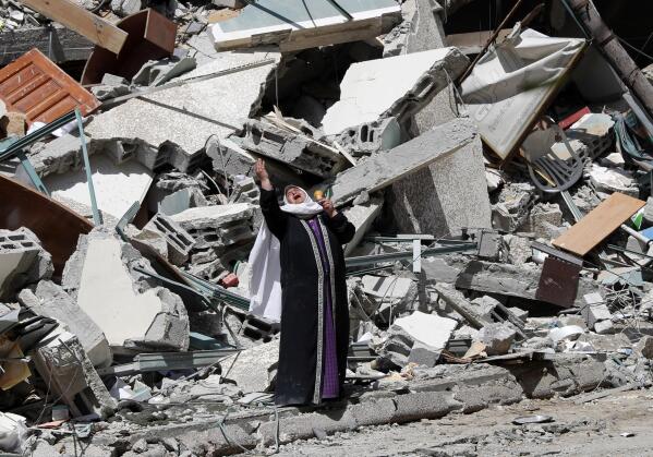A woman reacts while standing near the rubble of a building that was destroyed by an Israeli airstrike on Saturday that housed The Associated Press, broadcaster Al-Jazeera and other media outlets, in Gaza City, Sunday, May 16, 2021. (AP Photo/Adel Hana)