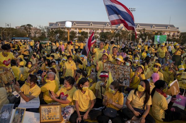 Supporters of Thai monarch display images of King Maha Vajiralongkorn, Queen Suthida and late King Bhumibol Adulyadej ahead of the arrival of king and queen to participate in a candle lighting ceremony to mark birth anniversary of late King Bhumibol Adulyadej at Sanam Luang ceremonial ground in Bangkok, Thailand, Saturday, Dec. 5, 2020. (AP Photo/Gemunu Amarasinghe)