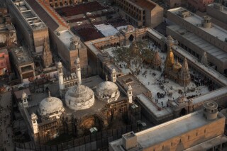 FILE- An Aerial view shows Gyanvapi mosque, left, and Kashiviswanath temple on the banks of the river Ganges in Varanasi, India, Dec. 12, 2021. An Indian court on Thursday ruled that officials can conduct a scientific survey to determine if the 17th-century mosque in the country's north was built over a Hindu temple. . (AP Photo/Rajesh Kumar Singh, File)