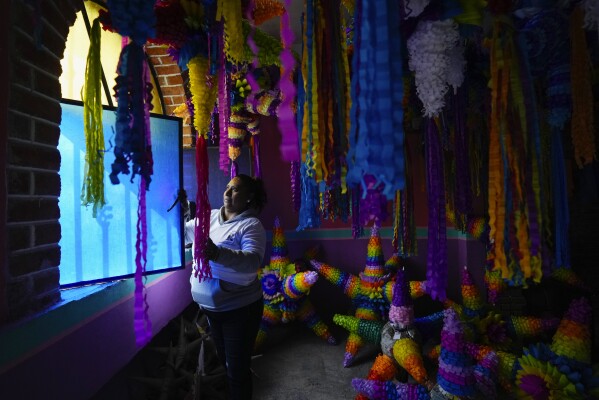 María de Lourdes Ortiz Zacarías vende piñatas en su pequeño negocio familiar de fabricación de piñatas en Acolman, justo al norte de la Ciudad de México, el miércoles 13 de diciembre de 2023. La familia inició su negocio en Acolman, donde la madre de Ortiz Zacarías era conocida como “la reina de las piñatas” antes de su muerte.  (Foto AP/Fernando Llano)