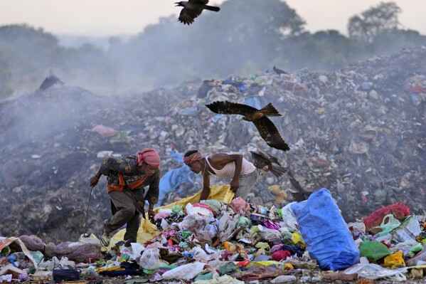 Waste pickers Salmaa and Usmaan Shekh, right, search for recyclable materials during a heat wave at a garbage dump on the outskirts of Jammu, India, Wednesday, June 19, 2024. Shekh and his family are among millions of people who scratch out a living searching through India's waste — and climate change is making a hazardous job more dangerous than ever. (ĢӰԺ Photo/Channi Anand)