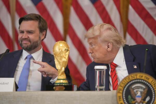 President Donald Trump gestures past Vice President JD Vance during a FIFA task force meeting on the 2026 FIFA World Cup in the East Room of the White House, Tuesday, May 6, 2025, in Washington. (AP Photo/Mark Schiefelbein)