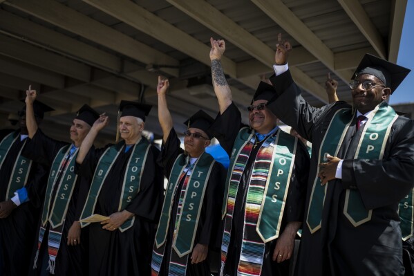 Incarcerated graduates, who finished their bachelor's degree program in communications through the Transforming Outcomes Project at Sacramento State (TOPSS), extend their pinky fingers during their graduation ceremony at Folsom State Prison in Folsom, Calif., Thursday, May 25, 2023. Many more prisoners will have opportunities to leave prison with bachelor's degrees when new federal rules on financial aid for higher education take effect in July. (AP Photo/Jae C. Hong)
