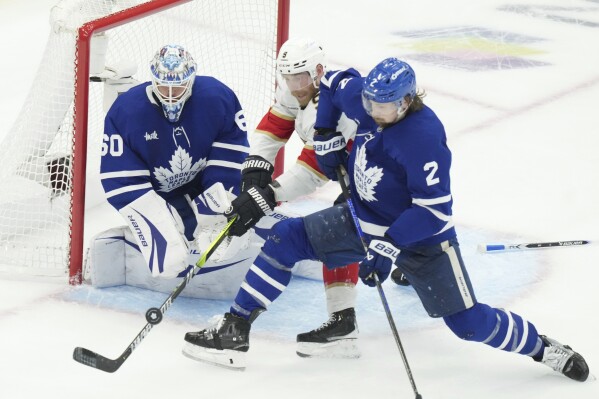 Florida Panthers centre Sam Bennett (9) and Toronto Maple Leafs defenceman Simon Benoit (2) vie for control of the puck in front of Leafs goalie Joseph Woll (60) during the second period of an NHL Stanley Cup playoff hockey game in Toronto, Sunday, May 18, 2025. (Chris Young/The Canadian Press via AP)