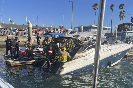 Long Beach firefighters inspect a charred vessel at Alamitos Bay in Long Beach, Calif., on Saturday, Aug. 5, 2023. Two women were killed and another woman and two men were hospitalized with burns after a weekend fire on the pleasure boat in Long Beach, California, authorities said. (Long Beach Fire Department via AP)
