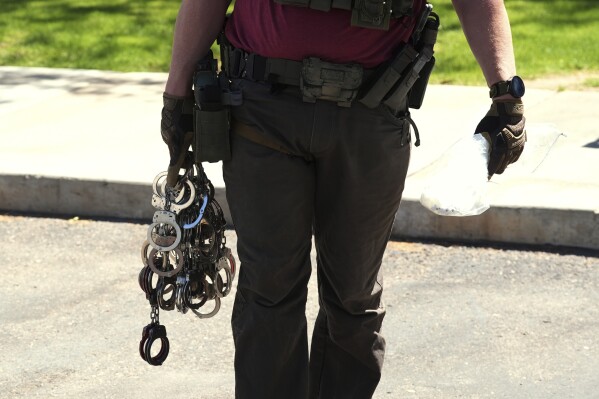 A federal agent holds handcuffs outside immigration court, May 21, 2025, in Phoenix. (AP Photo/Ross D. Franklin, File)