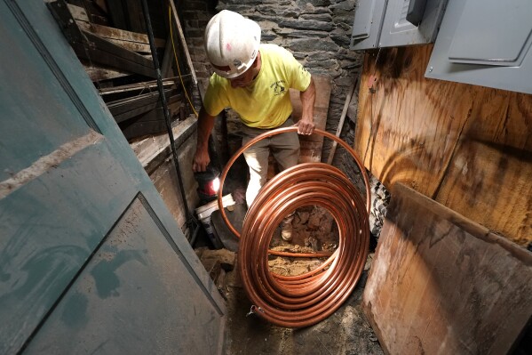 George Philbin, of Boyle & Fogarty Construction, works to feed a new copper residential water supply line, after removing a old lead residential water supply line, in the basement of a home where service was getting upgraded, Thursday, June 29, 2023, in Providence, R.I. (Health and environmental groups have been fighting for lead-free water to drink in Providence for at least a decade. (AP Photo/Charles Krupa)