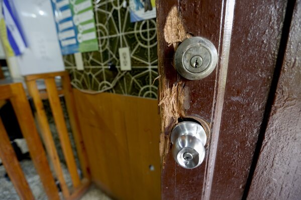 
              This Dec. 14, 2018 photo shows a door damaged by police when they forced their way into the offices of the Popol Na Foundation, in Managua, Nicaragua. The heavy-handed raids on the country’s most prominent non-governmental organizations and the seizure of the offices of the independent news outlets Confidencial and 100% Noticias left a clear message that no one _ especially former Sandinista comrades _ was safe from a crackdown on dissent following a wave of protests that increasingly aimed at pushing the 73-year-old president from power. (AP Photo/Alfredo Zuniga)
            