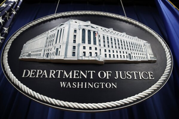 In this Thursday, April 18, 2019, file photo, a sign for the Department of Justice hangs in the press briefing room at the Justice Department, in Washington. (AP Photo/Patrick Semansky)