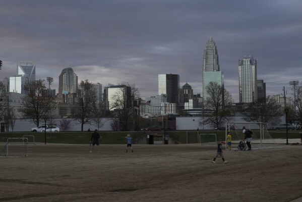 Children walk through a sports field in Independence Park under the skyline of Charlotte, N.C., on March 20, 2025. (AP Photo/Mary Conlon)