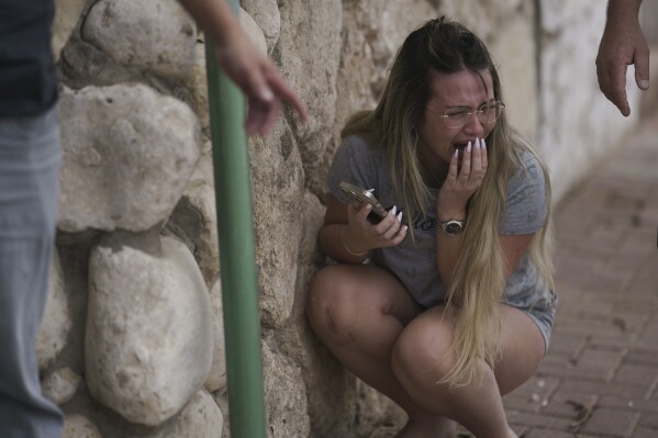 Người Israel ẩn nấp trước làn đạn tên lửa phóng tới từ Dải Gaza ở Ashkelon, miền nam Israel, Thứ Tư, ngày 11 tháng 10 năm 2023. (Ảnh AP / Leo Correa)