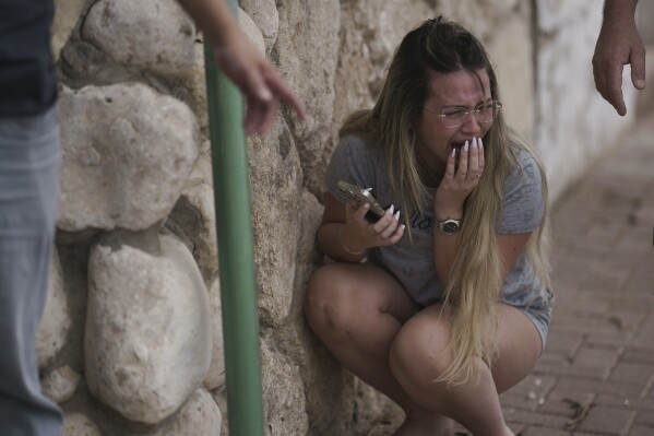 Israelis take cover from incoming rocket fire from the Gaza Strip in Ashkelon, southern Israel, Wednesday, Oct. 11, 2023. (AP Photo/Leo Correa)