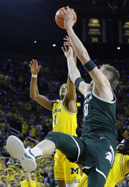 Michigan guard Nimari Burnett (4) and Michigan State forward Jaxon Kohler (0) battle for a rebound during the first half of an NCAA college basketball game Friday, Feb. 21, 2025, in Ann Arbor, Mich. (AP Photo/Duane Burleson)