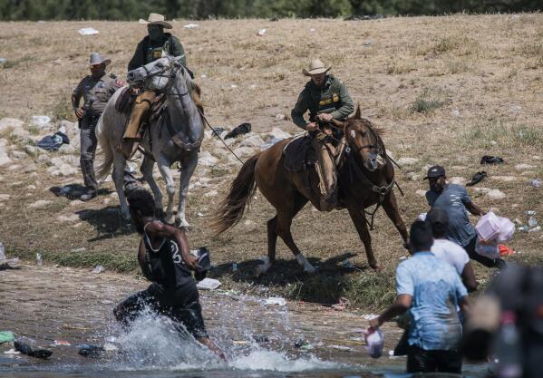U.S. Customs and Border Protection mounted officers attempt to contain migrants as they cross the Rio Grande from Ciudad Acuña, Mexico, into Del Rio, Texas, Sunday, Sept. 19, 2021. (AP Photo/Felix Marquez)