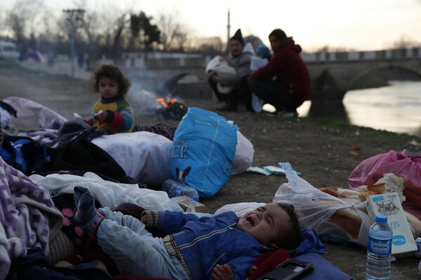 A baby cries as migrants gather next to a river in Edirne, Turkey, near Turkish-Greek border on Wednesday, March 4, 2020. Facing a potential wave of nearly a million people fleeing fighting in northern Syria, Turkey has thrown open its borders with Greece to thousands of refugees and other migrants trying to enter Europe, and has threatened to send "millions" more. (AP Photo/Darko Bandic)