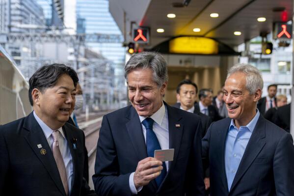 U.S. Secretary of State Antony Blinken, center, accompanied by U.S. Ambassador to Japan Rahm Emanuel, right, holds up his boarding card as he is greeted by Japan's Foreign Minister Yoshimasa Hayashi, left, as he boards a train at Tokyo Station in Tokyo, Sunday, April 16, 2023, to travel to Karuizawa, Japan for a G7 Foreign Ministers' Meeting. (AP Photo/Andrew Harnik, Pool)