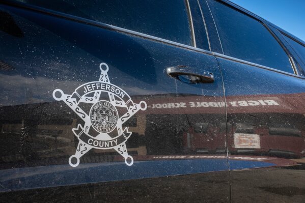This image provided by Idaho Education News shows the entrance to Rigby Middle School is seen in the reflection of a Jefferson County Sheriff's vehicle in Rigby, Idaho on Wednesday, Feb. 5, 2025. (John Roark/Idaho Education News via AP)
