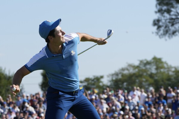 Europe's Viktor Hovland throws his ball to the crowd after winning his with playing partner Europe's Ludvig Aberg on the 15th green 4&3 morning Foursome match at the Ryder Cup golf tournament at the Marco Simone Golf Club in Guidonia Montecelio, Italy, Friday, Sept. 29, 2023. (AP Photo/Alessandra Tarantino)