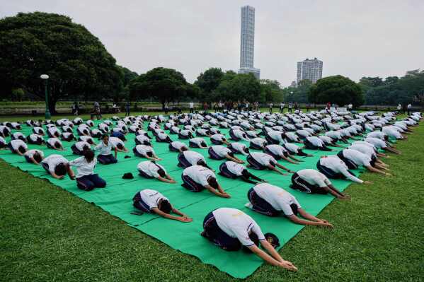 School boys and girls perform yoga on International Yoga Day at Victoria Memorial compound, in Kolkata, India, Saturday, June 21, 2025. (AP Photo/Bikas Das)