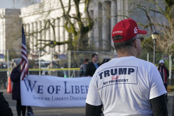 A supporter of President Donald Trump listens to speakers during a rally, Sunday, Jan. 10, 2021, at the Capitol in Olympia, Wash. Protesters from several causes rallied Sunday at the Capitol, which was secured with a perimeter fence and National Guard members, the day before the 2021 legislative session was scheduled to begin. (AP Photo/Ted S. Warren)