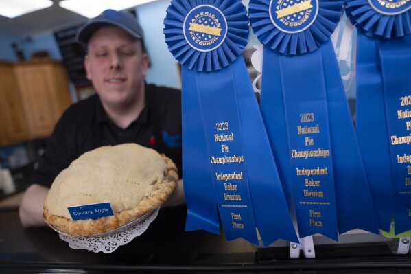 El gerente Stephen Jarrett muestra su pastel de manzana nacional ganador del primer lugar en el Campeonato Nacional de Pies en Michele's Pies, el miércoles 13 de marzo de 2024, en Norwalk, Connecticut. Los entusiastas de las matemáticas y los panaderos celebran el día Pi el 14 o 3/14 de marzo, los primeros tres dígitos de una constante matemática con muchos usos prácticos.  En todo el mundo, muchas personas celebran el día con un trozo de tarta dulce o salada.  (Foto AP/John Minchillo)