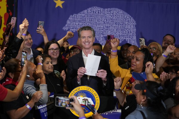 FILE - California Gov. Gavin Newsom signs the fast food bill surrounded by fast food workers at the SEIU Local 721 in Los Angeles, on Thursday, Sept. 28, 2023. Republican leaders in California are calling for an investigation into why a new state law requiring a $20 minimum wage for fast food workers includes an exemption for restaurants like Panera Bread. (AP Photo/Damian Dovarganes, File)