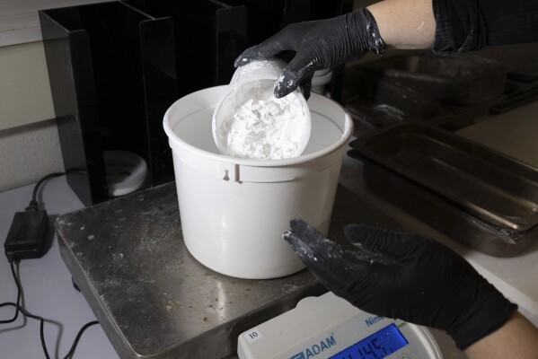 A worker measures ReAct product at Fortera's facility in San Jose, Calif., Wednesday, April 10, 2024. The cement industry is one of the largest emitters of carbon dioxide and is responsible for about 8% of global emissions each year. Fortera, a clean tech company whose technology captures carbon emissions from kilns and feeds it back in to the process, is opening its first commercial scale operation on Thursday, April 12, 2024, in California. (AP Photo/Benjamin Fanjoy)