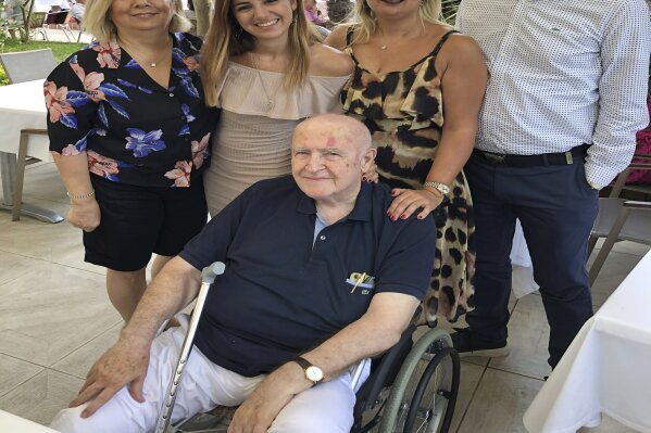 In this family photo provided by Dr. Caner Dilmener, Dr. Murat Dilmener, seated in a wheelchair, a professor of infectious diseases in Istanbul is pictured June 9, 2019, with other family members during a family Sunday lunch at Buyuk Klup (Cercle d'Orient) in Istanbul. Dr. Murat Dilmener died May 3, 2020, at age 78, of COVID-19 at the Maltepe Medical Faculty Hospital in Istanbul. His charity and compassion would inspire Turkish newspapers to dub Dilmener the “Robin Hood of the medical profession” and earn the professor and practicing physician the admiration of thousands of patients and students. (Courtesy of Caner Dilmener via AP)