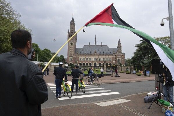 A lone demonstrator waves the Palestinian flag outside the Peace Palace, rear, housing the International Court of Justice, or World Court, in The Hague, Netherlands, on May 24, 2024. (AP Photo/Peter Dejong, File)