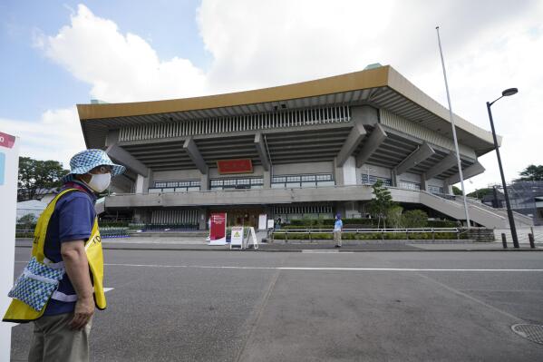A volunteer works outside the Nippon Budokan stadium for judo ahead of the 2020 Summer Olympics, Friday, July 23, 2021, in Tokyo, Japan. (AP Photo/Vincent Thian)