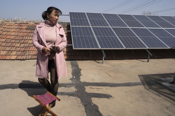 2024年3月21日，中国东部山东省济南市郊区，农民史梅（Shi Mei）走在屋顶上的太阳能电池板附近。施氏家族处于中国太阳能热潮的前沿，长期以来，中国一直主导着全球太阳能制造业，但并不总是在国内安装大量太阳能。她每发一瓦特的电都会得到报酬。（美联社照片/吴汉观）