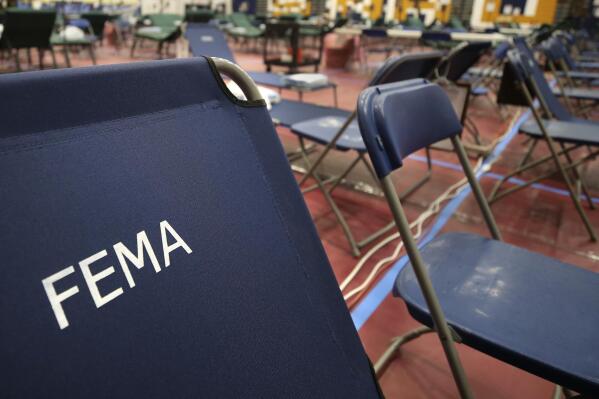 FILE - A portable cot, with the Federal Emergency Management Agency logo FEMA printed on the backrest, and other cots line the basketball court at a makeshift medical facility in a gymnasium at Southern New Hampshire University in Manchester, N.H., March 24, 2020. FEMA may have been double-billed for the funerals of hundreds of people who died of COVID-19, the Government Accountability Office said in a new report Wednesday, April 27, 2022. (AP Photo/Charles Krupa, File)