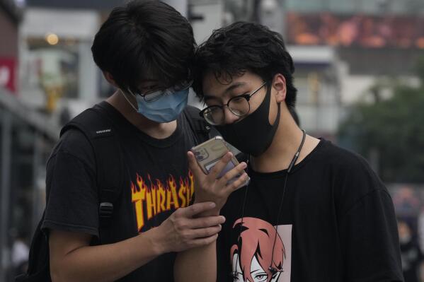 Men look at a smartphone in Beijing on Monday, July 5, 2021. Days after China's largest ride-hailing app Didi Global Inc. went public in New York as the biggest Chinese IPO in the U.S. since Alibaba's 2014 listing, Chinese regulators clamped down on the firm, ordering it to halt new registrations and remove its app from China's app stores while the company undergoes a cybersecurity review. (AP Photo/Ng Han Guan)