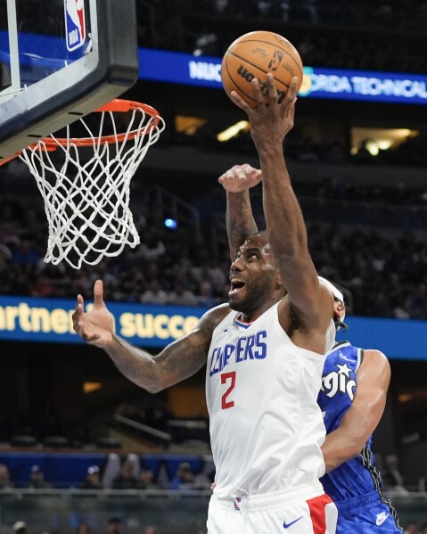 Los Angeles Clippers forward Kawhi Leonard (2) makes a shot as he gets past Orlando Magic forward Paolo Banchero, back right, during the second half of an NBA basketball game, Friday, March 29, 2024, in Orlando, Fla. (AP Photo/John Raoux)