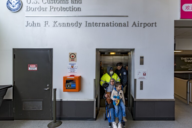 Four-year-old Omar Abu Kuwaik, and his aunt Maha Abu Kuwaik, both from Gaza, are escorted through John F. Kennedy International Airport after departing a flight from Egypt on Wednesday, Jan. 17, 2024, in New York. (AP Photo/Peter K. Afriyie)