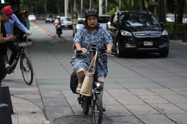 FILE - Senator Xochitl Galvez, an opposition presidential hopeful, rides a bike upon her arrival to a hotel for the announcement of the opposition presidential candidates in Mexico City, Wednesday, Aug. 9, 2023. The main opposition parties declared on Wednesday, August 30, 2023, Galvez as their virtual candidate for the upcoming presidential elections. (AP Photo/Fernando Llano, File)