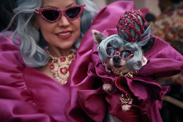 A reveler wearing decorated hats and costumes hold her dog as she participates in the annual Easter Parade and Bonnet Festival in front of St. Patrick's Cathedral on Sunday, April 20, 2025, in New York. (AP Photo/Andres Kudacki)