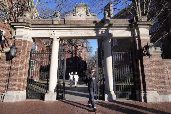 FILE - A passer-by walks through a gate to the Harvard University campus, Tuesday, Jan. 2, 2024, in Cambridge, Mass. Harvard University, struggling to manage the campus response to the Israel-Hamas war, announced plans Friday, Jan. 19, to create task forces to combat antisemitism and anti-Arab bias. (AP Photo/Steven Senne)