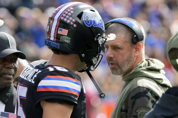 Florida head coach Billy Napier, right, talks with quarterback Graham Mertz during a timeout in the first half of an NCAA college football game against Arkansas, Saturday, Nov. 4, 2023, in Gainesville, Fla. (AP Photo/John Raoux)